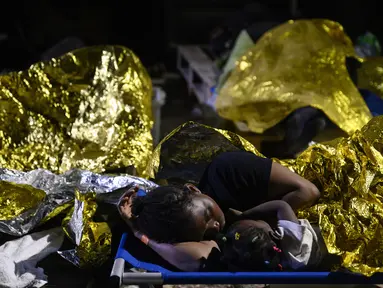 Seorang perempuan dan seorang anak tidur di luar pusat penerimaan migran Lampedusa, Sisilia, Kamis pagi, 14 September 2023. (AP Photo/Valeria Ferraro)