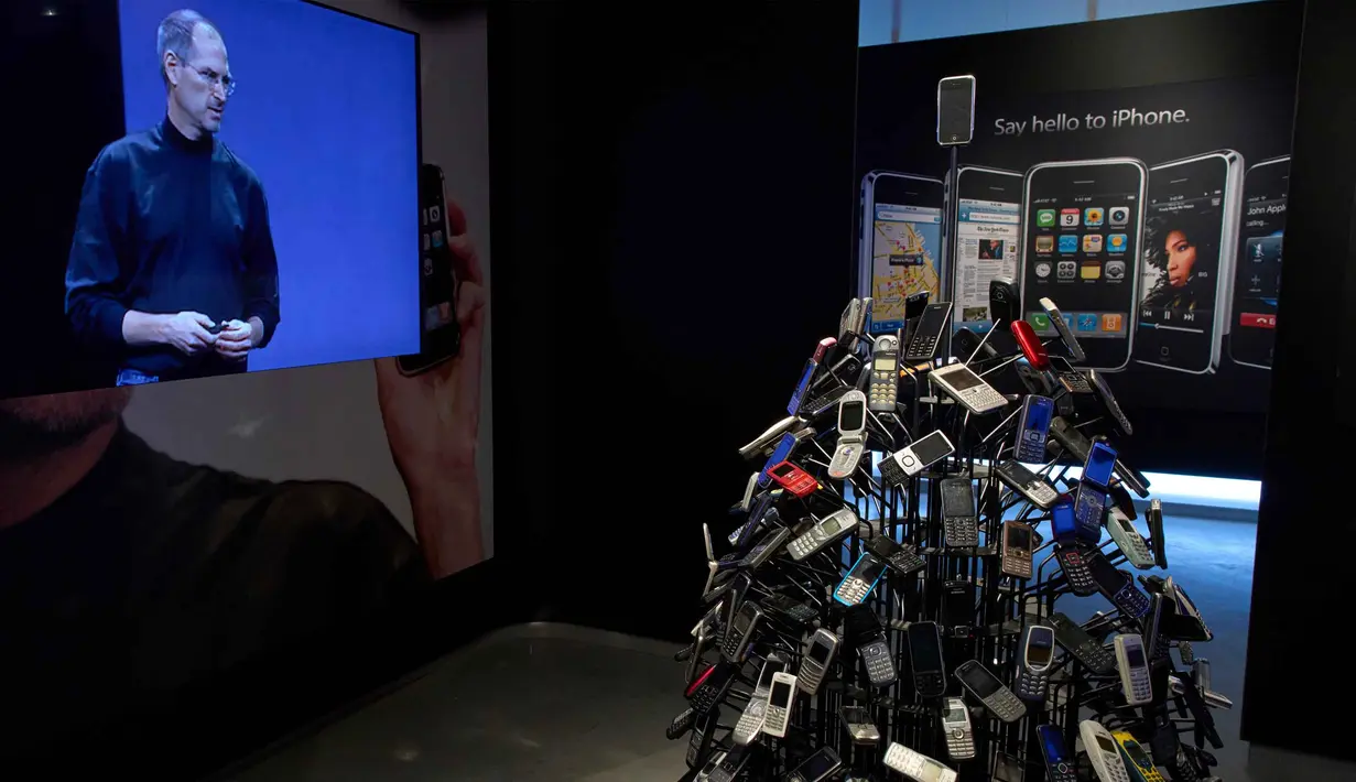 Untuk diketahui, Apple didirikan pada 1 April 1976 dengan semangat untuk menantang kebiasaan lama dan menghadirkan cara baru dalam memanfaatkan teknologi. Tampak dalam foto, iPhone dan video mantan CEO Apple Steve Jobs terlihat di Museum Apple baru yang menelusuri 50 tahun inovasi merek ikonik tersebut, di Utrecht, Belanda, Rabu, 1 April 2026. (AP Photo/Peter Dejong)