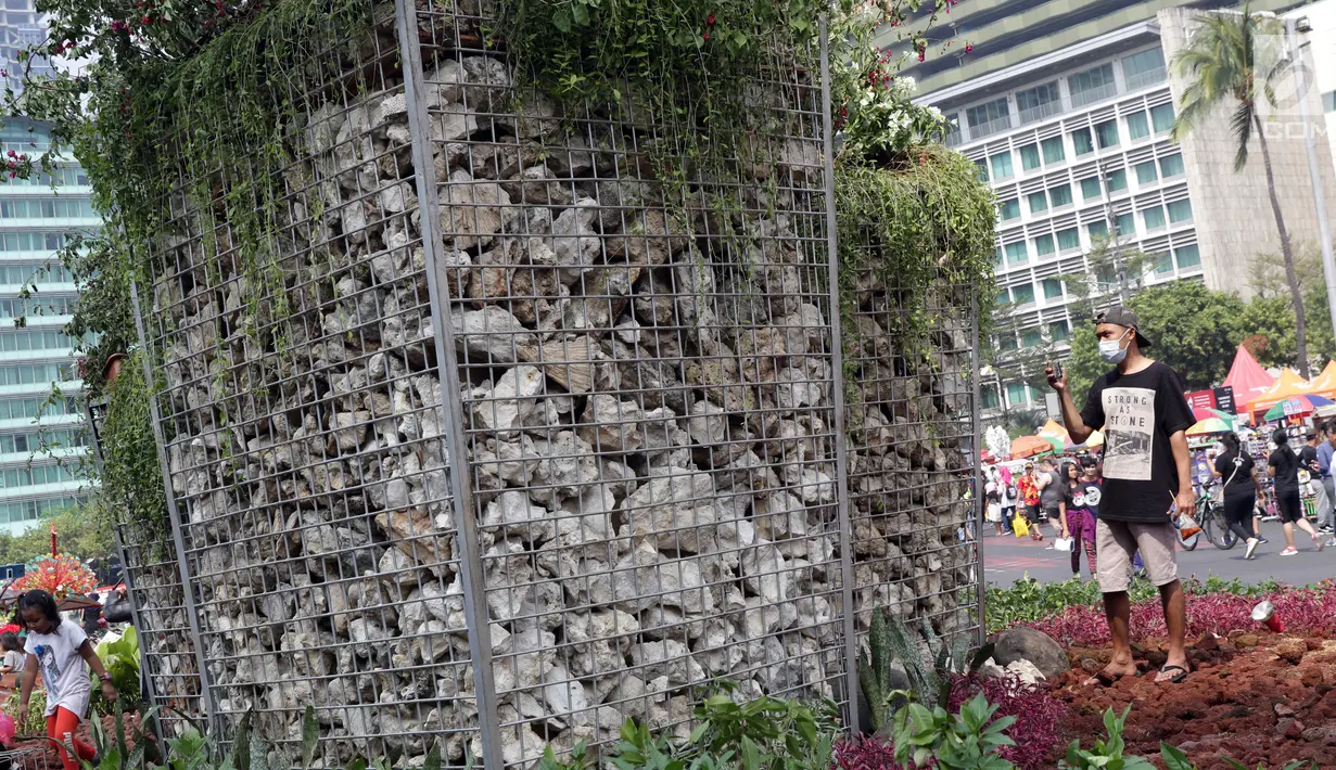 Salah satu warga memotret Instalasi Gabion saat CFD di kawasan Bundaran Hotel Indonesia, Jakarta, Minggu (25/8/2019). Pengadaan Instalasi Gabion ini menggunakan Anggaran Pendapatan dan Belanja Daerah (APBD) Dinas Kehutanan DKI sebesar Rp 150 juta. (Liputan6.com/Helmi Fithriansyah)