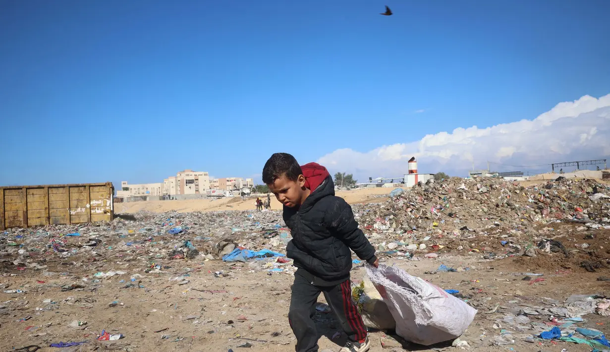 Data Kementerian Kesehatan Palestina di Gaza, pada Rabu (20/11/2024), mengungkap setidaknya 17.400 anak-anak menjadi korban serangan Israel. Tampak dalam foto, seorang anak laki-laki Palestina mengumpulkan barang-barang yang ia temukan di tumpukan sampah yang dapat digunakan kembali di kota Khan Yunis, Jalur Gaza selatan pada 19 November 2024 (Eyad BABA/AFP)