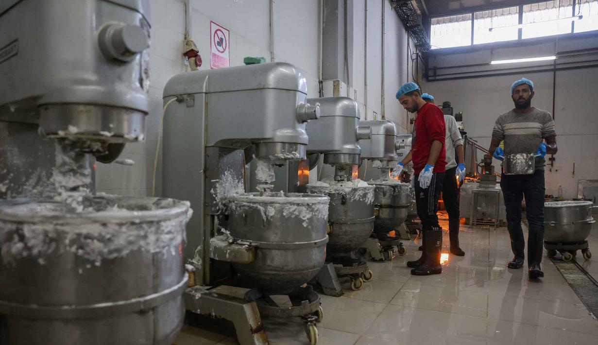 Untuk sementara, pabrik Al-Arees memprioritaskan pemulihan lini produksi untuk permen al-Shatwi yang sangat populer, terutama di musim dingin. Tampak dalam foto, para pekerja Palestina menyiapkan isian kue manis yang dikenal secara lokal sebagai "al-Shatwi" (kue musim dingin) Crimbo, saat pabrik Al-Arees secara bertahap melanjutkan produksinya setelah terhenti akibat perang, di Deir al-Balah, Jalur Gaza tengah pada 12 Januari 2026, (Bashar Taleb/AFP)