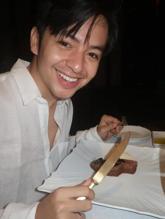 Sebagai pasangan yang selalu tampil serasi, Angga Yunanda memilih gaya minimalis dan klasik dengan mengenakan kemeja linen putih longgar. Outfit ini memberikan kesan effortless elegance, sangat cocok untuk suasana dinner romantis. [@angga/@sheninacinnamon].