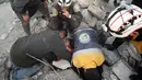 Anggota Syrian Civil Defence atau White Helmets berusaha menyelamatkan gadis yang tertimpa puing bangunan usai serangan udara pasukan pemerintah di Desa Tal Mardikh, Provinsi Idlib, Suriah, Kamis (19/12/2019). Pasukan Suriah kian intens menyerang Idlib. (Omar HAJ KADOUR/AFP)