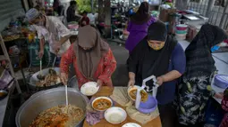 Sukarelawan memindahkan makanan ke dalam kotak di Masjid Bang Aw, Bangkok, Thailand, Kamis (30/4/2020). Setiap hari selama Ramadan, sukarelawan membagikan makanan kepada 150 keluarga sekitar Masjid Bang Aw yang tidak bisa beribadah bersama karena pandemi COVID-19. (AP Photo/Gemunu Amarasinghe)
