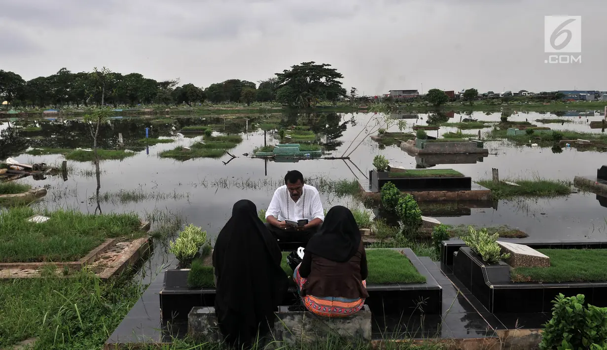 Peziarah berdoa di TPU Semper yang terendam banjir, Jakarta, Selasa (4/12). TPU Semper menjadi langganan banjir saat musim penghujan akibat rendahnya permukaan tanah dengan ketinggian air sepinggang orang dewasa. (Merdeka.com/Iqbal S. Nugroho)