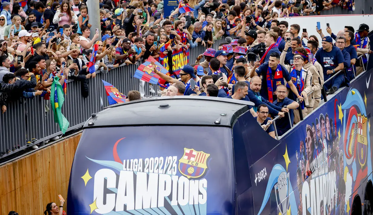 <p>Pemain Barcelona melakukan parade bus terbuka melalui Ibu Kota Catalan, menyapa para penggemar yang bernyanyi, dan melambai-lambaikan bendera sementara kembang api dan suar dinyalakan.&nbsp;(AP Photo/Joan Monfort)</p>