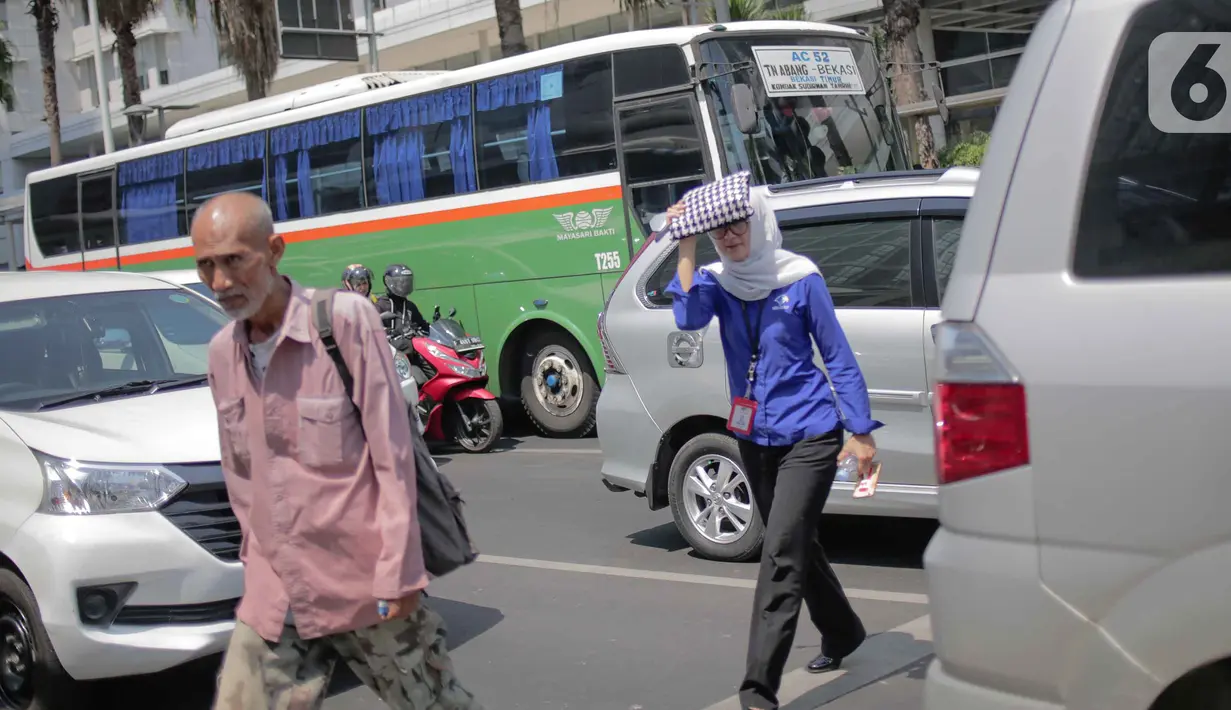 Seorang wanita menyebrang selama gelombang panas di Jakarta, Selasa (22/10/2019).  BMKG memprediksi wilayah Indonesia akan mengalami panas selama kurang lebih satu minggu ini. Hal ini dikarenakan matahari yang berada dekat dengan jalur khatulistiwa. (Liputan6.com/Faizal Fanani)