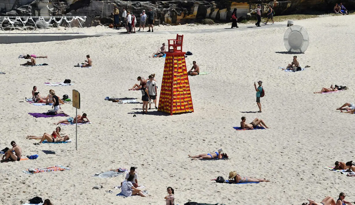 Pengunjung berjemur di dekat patung seniman Linton Meagher selama pameran "Sculpture by the Sea" di dekat pantai Bondi di Sydney (19/10). Pameran ini menampilkan lebih dari 100 patung karya seniman dari Australia dan seluruh dunia. (AFP Photo/Saeed Khan)