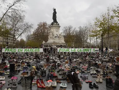 Ribuan pasang sepatu yang dikirimkan aktivis dipajang di place de la Republique, Prancis, sebagai tanda solidaritas karena pawai lingkungan di Paris dibatalkan jelang Konferensi Tingkat Tinggi Perubahan Iklim, Minggu (29/11).  (AFP PHOTO/Miguel Medina)