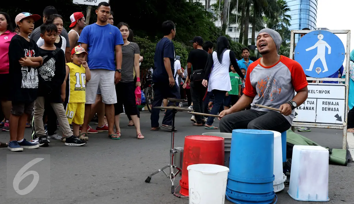 Pengamen perkusi sedang beraksi ditonton para pengunjung saat CFD, Jakarta, Minggu (10/9). Di sepanjang jalan lokasi CFD terdapat aneka kegiatan seperti olahraga, berjualan dan  mengamen. (Liputan6.com/Gempur M. Surya)
