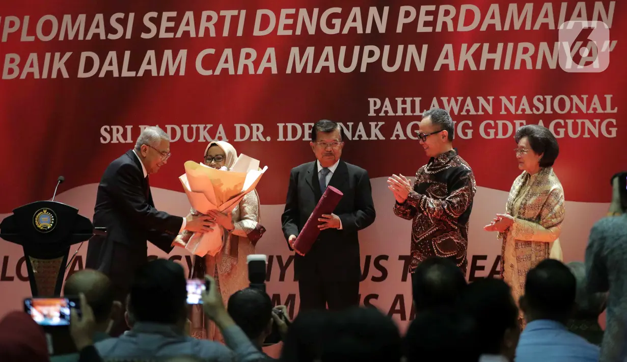 Wakil Presiden ke-10 dan ke-12 RI Jusuf Kalla (tengah) saat menerima anugerah dari Pembina Yayasan Sekar Manggis Anak Agung Gde Agung (kiri) saat penyerahan penghargaan Anugerah Dr Ide Anak Agung Gde Agung di Kantor Kementerian Luar Negeri, Jakarta, Kamis (23/1/2020). (Liputan6.com/Faizal Fanani)