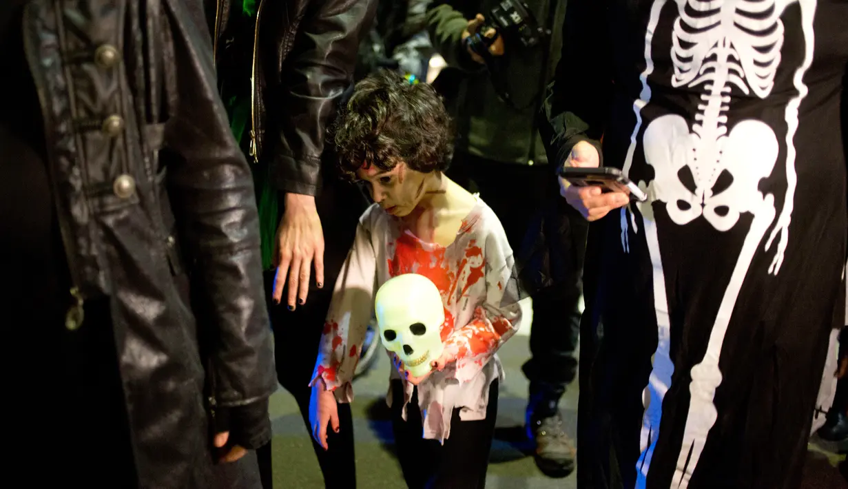 Seorang bocah mengenakan kostum zombie saat mengikuti Zombie Walk dalam Festival Purim di Tel Aviv, Israel (3/3). Purim merupakan hari raya atau pesta Yahudi untuk memperingati pembebasan kaum Yahudi dari kekaisaran Persia. (AP Photo/Ariel Schalit)