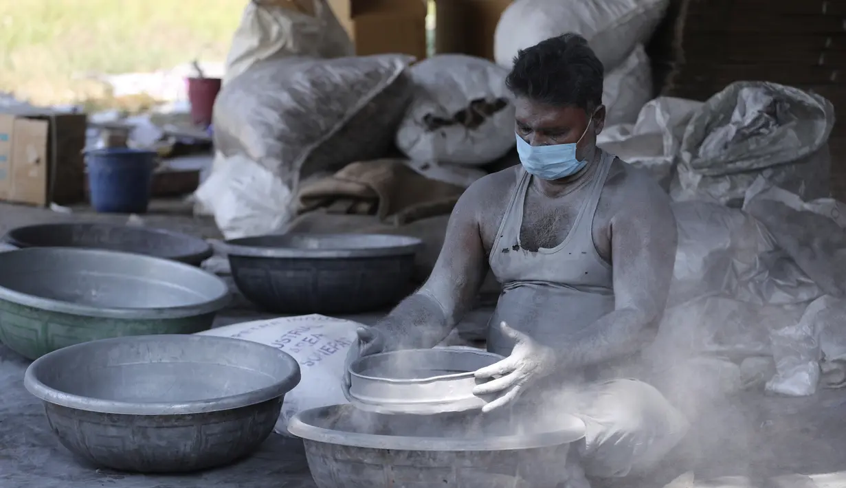 Pekerja mengenakan masker membuat petasan untuk festival Hindu Diwali yang akan datang di Ahmedabad, India, 28 Oktober 2020. Pihak berwenang sedang mempersiapkan diri menghadapi gelombang baru Covid-19, setelah festival keagamaan terpenting di negara itu, akan digelar pada November (AP/Ajit Solanki)