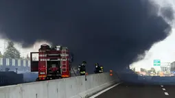 Petugas pemadam kebakaran berada di lokasi ledakan truk tangki yang membawa bahan mudah terbakar di jalan raya dekat kota Bologna, Italia, Senin (6/8). Kuatnya ledakan bahkan sampai menyebabkan jalan layang rusak. (AFP/Gianni SCHICCHI)