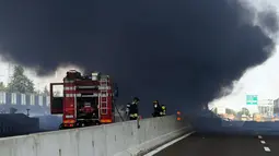 Petugas pemadam kebakaran berada di lokasi ledakan truk tangki yang membawa bahan mudah terbakar di jalan raya dekat kota Bologna, Italia, Senin (6/8). Kuatnya ledakan bahkan sampai menyebabkan jalan layang rusak. (AFP/Gianni SCHICCHI)