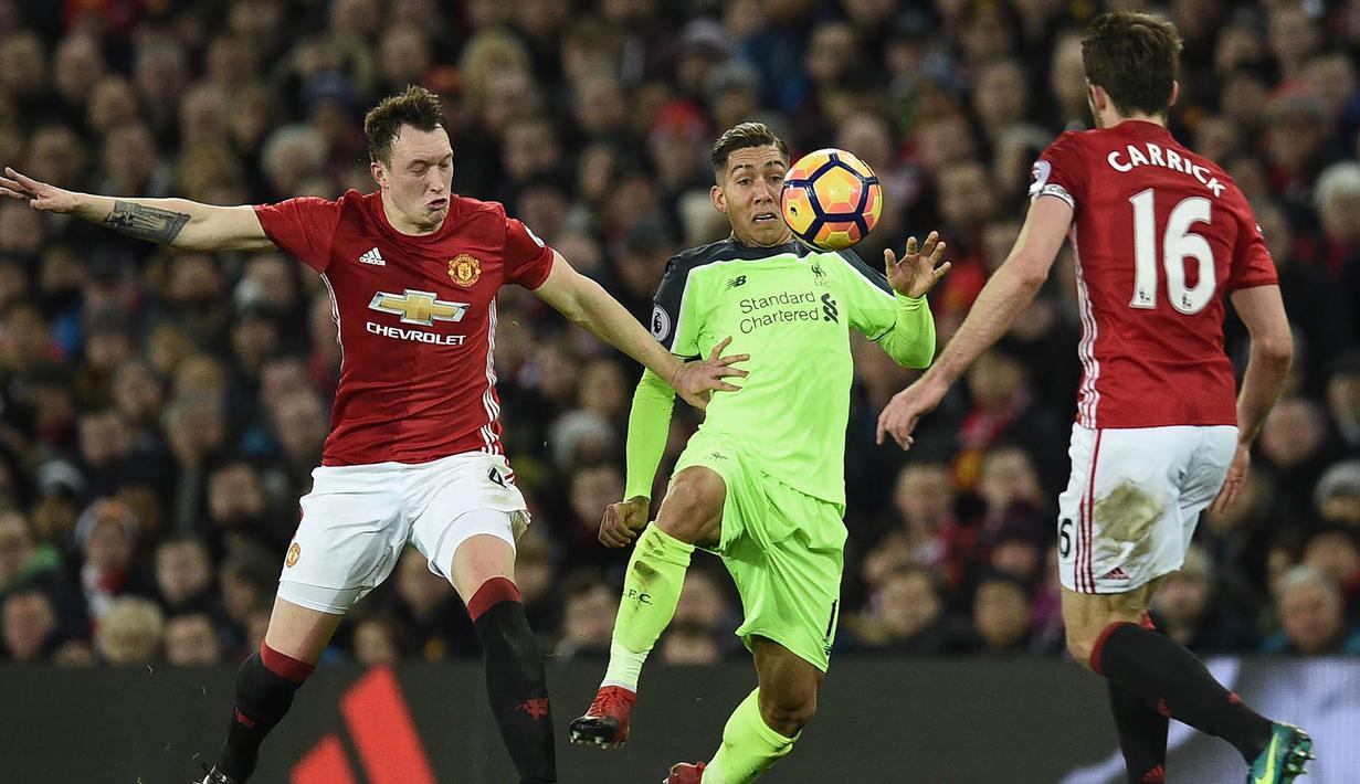 Gelandang Liverpool, Roberto Firmino, berusaha melewati hadangan bek Manchester United, Phil Jones. Pada laga ini kedua tim turun dengan formasi 4-3-3 dan tampil dengan komposisi pemain terbaiknya. (AFP/Oli Scarff)