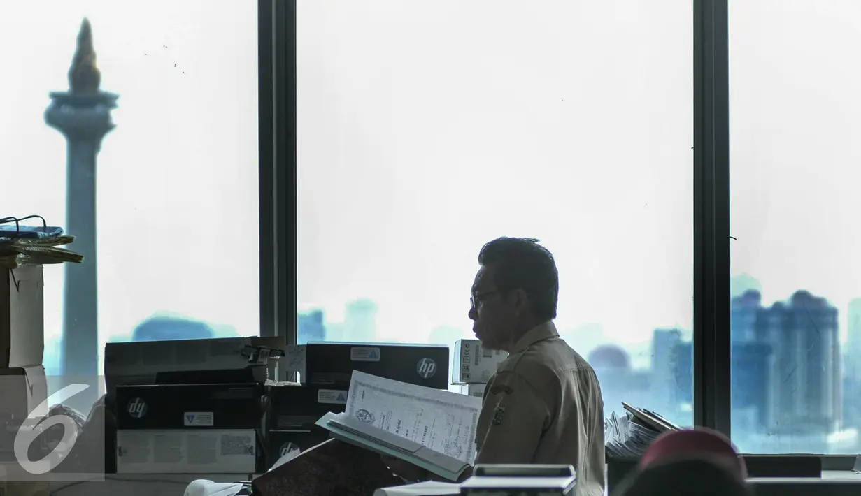 Seorang PNS saat membaca dokumen di ruanganya, Jakarta, Senin (11/7). Gubernur DKI Jakarta Basuki T Purnama  mengancam akan memberikan sanksi hingga pemecatan kepada PNS DKI apabila tidak masuk usai libur lebaran. (Liputan6.com/Yoppy Renato)