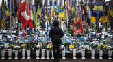 Seorang warga setempat berdiri di depan tugu peringatan sementara untuk tentara Ukraina di Lapangan Kemerdekaan, Kyiv, saat peringatan keempat invasi Rusia ke Ukraina, Selasa 24 Februari 2026. Hari ini, perang Rusia-Ukraina yang pecah pada 24 Februari 2022 telah berlangsung selama empat tahun. (HENRY NICHOLLS/AFP)