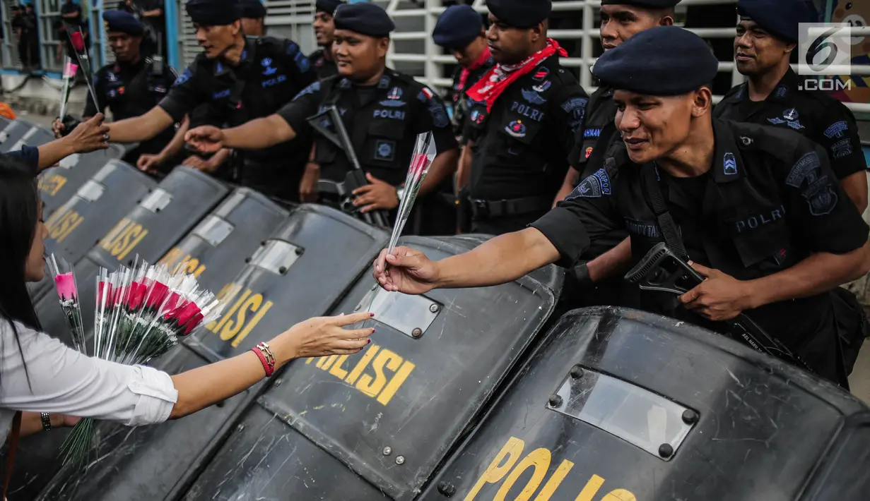 Petugas Brimob menerima bunga dari peserta aksi komunitas Spartan Nusantara di sekitar Gedung Bawaslu, Jakarta, Minggu (26/5/2019). Aksi tersebut sebagai bentuk terima kasih kepada TNI/Polri karena setia dan menjaga keamanan NKRI terkait sengketa pemilu. (Liputan6.com/Faizal Fanani)