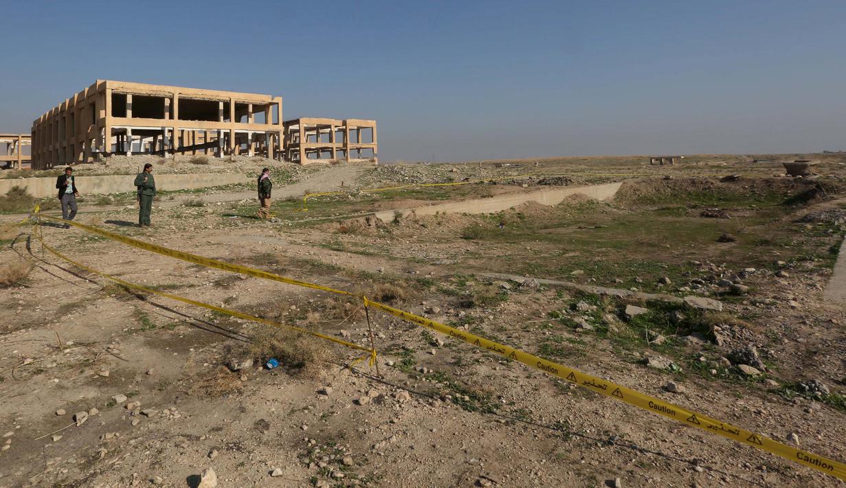 Pasukan Kurdi berdiri di sekitar kuburan massal yang diduga lokasi makam anggota Yazidi Irak di pinggiran kota Sinjar, 30 November 2015. Pasukan Kurdi menemukan kuburan ini usai berhasil merebut kembali kota Irak dari militan ISIS. (Reuters/Ari Jalal)