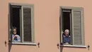 Penghuni apartemen menyaksikan perayaan Minggu Palma di Roma, Italia, 5 April 2020. Menurut Departemen Perlindungan Sipil Italia pada 6 April 2020, jumlah kasus virus corona COVID-19 di negara tersebut menjadi 132.547 infeksi, 16.523 meninggal, dan 22.837 sembuh. (Tiziana FABI/AFP)