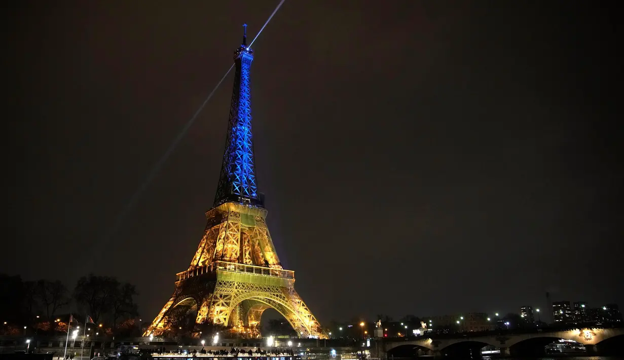 Menara Eiffel diterangi dengan warna-warna khas Ukraina untuk menandai peringatan satu tahun invasi Rusia ke negara tersebut, di Paris, Kamis, 23 Januari 2023. Invasi Rusia ke Ukraina merupakan salah satu yang terbesar di Eropa sejak Perang Dunia II, ratusan ribu jiwa menjadi korban di kedua pihak, serta menciptakan krisis pengungsi terbesar di Eropa. (AP Photo/Christophe Ena)