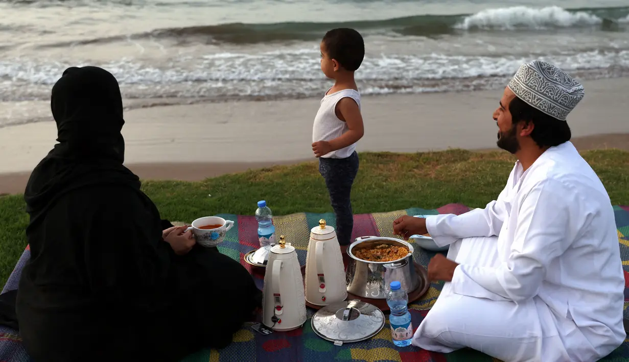 Sebuah keluarga Oman berkumpul untuk berbuka puasa di pantai di Muscat selama bulan suci Ramadhan pada 12 April 2022. Umat islam di seluruh dunia saat ini tengah melaksanakan bulan Ramadhan dan berpuasa selama satu bulan. (MOHAMMED MAHJOUB / AFP)