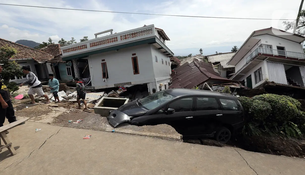 Mobil terperosok ke dalam jalan yang ambles akibat gempa di Desa Sarampad, Kabupaten Cianjur, Jawa Barat, Selasa (22/11/2022). Warga yang terdampak gempa berharap bantuan seperti makanan, obat-obatan, selimut, dan petugas medis bisa segera datang. (Liputan6.com/Herman Zakharia)