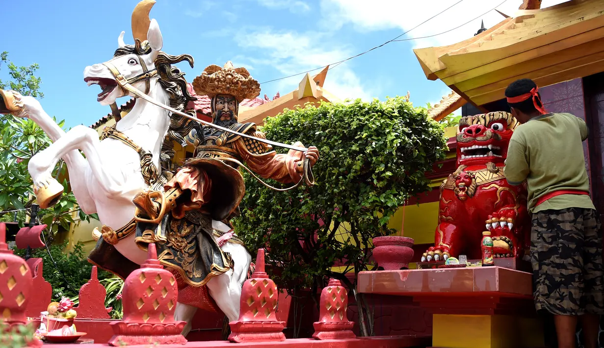 Seorang pekerja mengecat patung di depan kuil Cina di Denpasar, Bali, Senin (23/1). Pengecatan ini dilakukan dalam rangka menyambut pergantian tahun baru Imlek 2568. (AFP PHOTO / SONNY Tumbelaka)