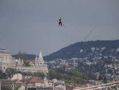 Seniman sirkus berusia 63 tahun Laszlo Simet berjalan di atas tali melintasi dua tepi sungai Danube di pusat kota Budapest pada Sabtu, 15 April 2023. (AP Photo/Denes Erdos)