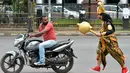 Seorang seniman berpakaian seperti "Yamaraj" (R), dewa kematian Hindu, berjalan mengejar pengendara motor tanpa helm sebagai bagian kampanye 'Road Safety Week' yang diselenggarakan oleh polisi lalu lintas di Bangalore (10/7). (AFP Photo/Manjunath Kiran)