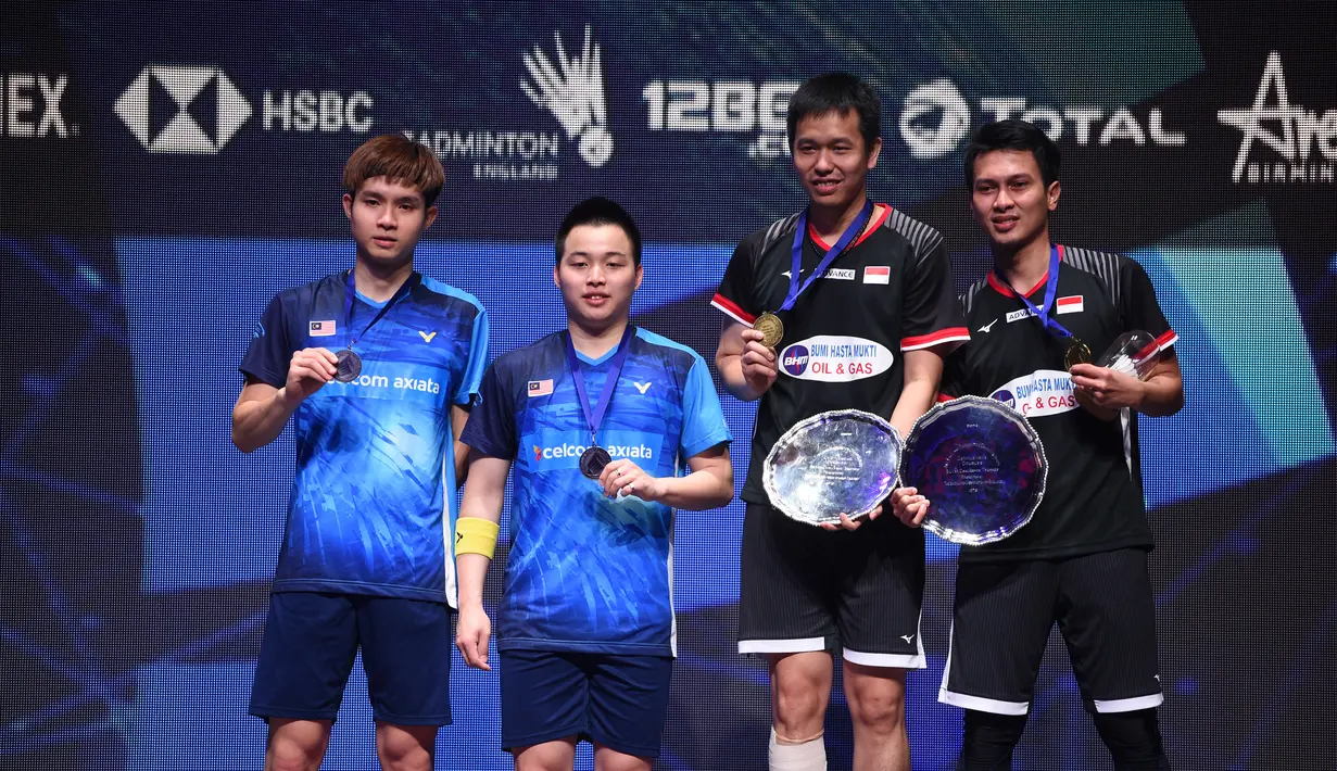 Pasangan Aaron Chia/Soh Wooi Yik dan Hendra Setiawan/Mohammad Ahsan pamer medali All England 2019. Hasil tersebut membuat pasangan Malaysia naik ke peringkat 15, sedangkan Hendra/Ahsan amankan peringkat 4 dunia. (AFP/Oli Scarff)