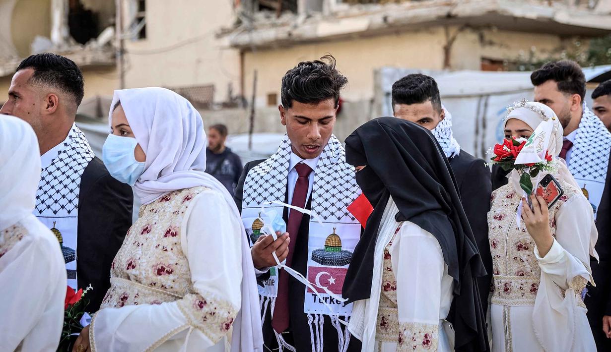 Suasana haru dan bahagia terlihat ketika para pasangan berjalan bersama di tengah sorakan dan tepuk tangan warga yang merayakan momen istimewa itu. Tampak dalam foto, para pengantin Palestina berkumpul selama perayaan pernikahan massal untuk para pengantin Palestina yang diselenggarakan oleh Yayasan Bantuan Kemanusiaan Turki (IHH) di Kota Gaza pada 11 Mei 2026. (Omar AL-QATTAA/AFP)