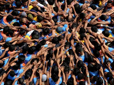 Pemuda India membentuk piramida manusia dalam perayaan Festival Janmashtami di Mumbai, Senin (3/9). Piramida manusia itu dibentuk untuk memecahkan pot berisikan susu yang menggantung di langit-langit rumah supaya bisa diambil isinya. (AP/Rafiq Maqbool)