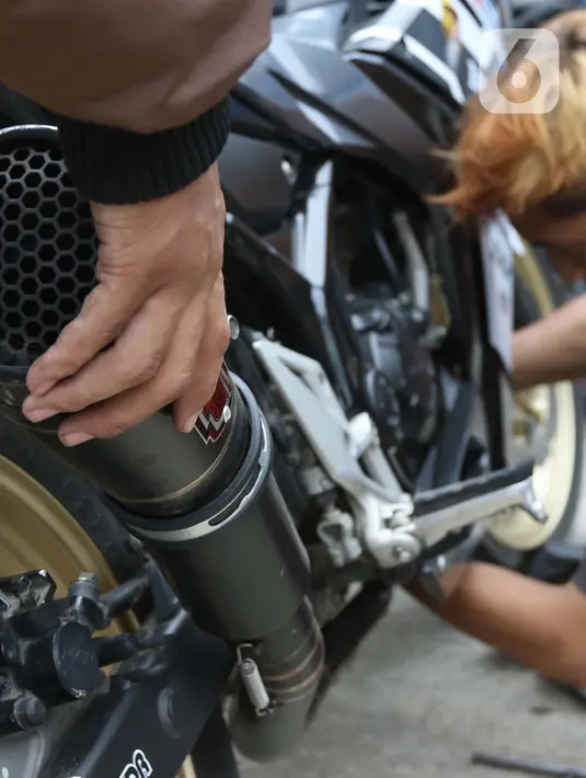 Pengendara motor mencopot knalpot bising usai terjaring razia yang digelar Satlantas Polres Metro Depok di Jalan Margonda Raya, Depok, Kamis (18/3/2021). Puluhan motor berknalpot bising yang terjaring razia diwajibkan mengganti knalpot dan diberi sanksi tilang. (Liputan6.com/Helmi Fithriansyah)