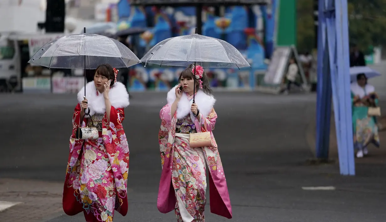 Dua wanita Jepang berjalan di bawah naungan payung dan balutan kimono usai menghadiri Coming of Age Day atau Hari Kedewasaan di Taman Toshimaen, Tokyo, Jepang, Senin, (8/1). (AP Photo/Shizuo Kambayashi)