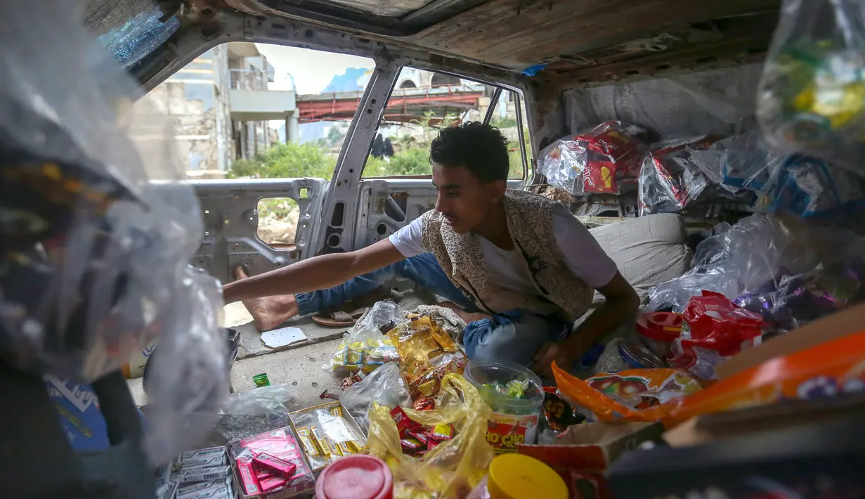 Majd al-Din al-Shamiri (16) menunggu pembeli di toko darurat di kawasan Jabal Sabr, Yaman pada 28 September 2019. Majd al-Din al-Shamiri mengubah mobil keluarganya yang rusak parah, akibat perang yang melanda, menjadi toko darurat untuk membantu keluarganya mencari nafkah. (Ahmad AL-BASHA/AFP)