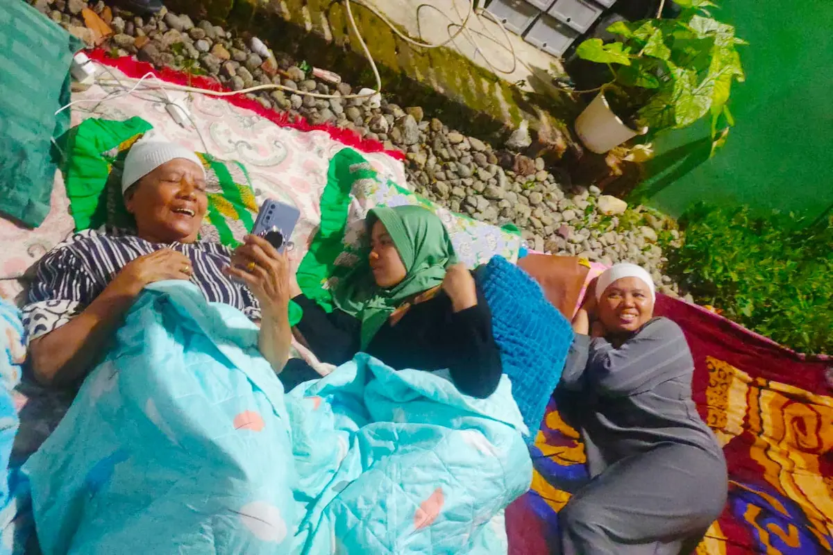 Emak-emak di Bawean nampak tersenyum saat bicara dengan kerabatnya melalui handphone. (Istimewa)