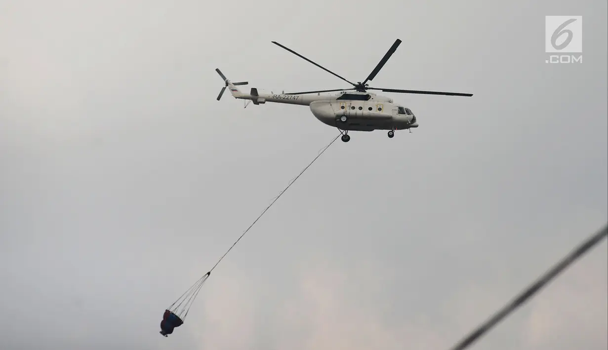 Helikopter water bombing membawa air untuk disiramkan ke arah ban yang dibakar massa di kawasan Slipi, Jakarta, Rabu (22/5/2019). Air dijatuhkan dari udara ke arah api yang berasal dari ban bekas. (merdeka.com/Imam Buhori)