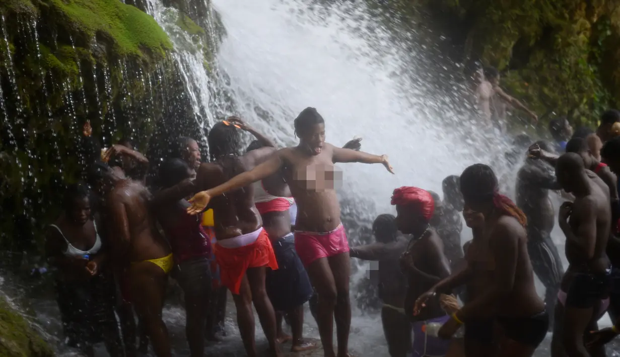 Sejumlah wanita bertelanjang dada mandi di bawah air terjun di Saut d' Eau, Haiti (15/7). Ritual ini juga dipercaya untuk menghormati Bunda Maria dari Gunung Karamel. (AFP Photo/Hektor Retamal)