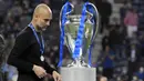 Pelatih Manchester City, Pep Guardiola, tertunduk lesu saat melintas di depan trofi usai ditaklukkan Chelsea pada laga final Liga Champions di Stadion Dragao, Porto, Minggu (30/5/2021). City takluk dengan skor 1-0. (Pierre Philippe Marcou/Pool via AP)