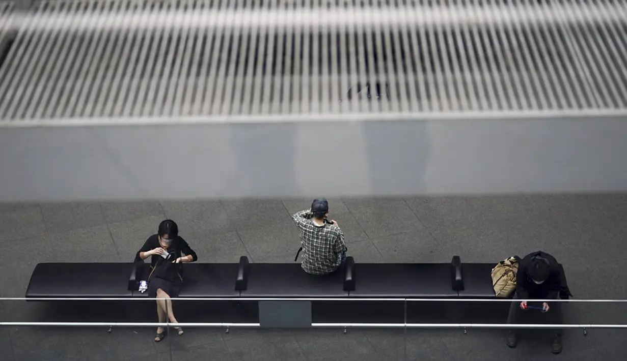 Orang-orang yang memakai masker untuk membantu mengekang penyebaran COVID-19 beristirahat di sebuah gedung di Tokyo, Jepang, Senin (2/11/2020). Tokyo mengonfirmasi lebih dari 80 kasus baru COVID-19 pada 2 Oktober 2020. (AP Photo/Eugene Hoshiko)