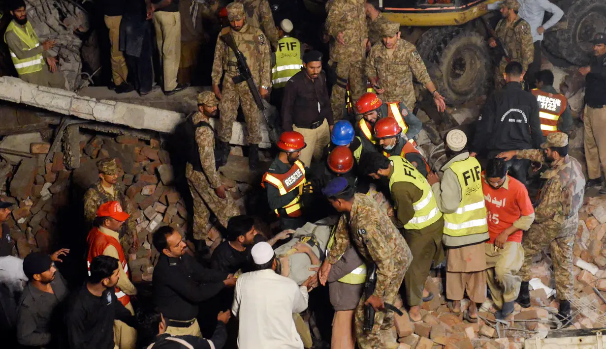 Tim SAR mengevakusi salah satu korban dari puing reruntuhan pabrik berlantai lima yang ambruk di Lahore, Pakistan Timur, Rabu (4/11) malam waktu setempat. Sedikitnya 16 orang tewas dan 40 luka-luka akibat kejadian tersebut. (AFP PHOTO/Arif Ali)