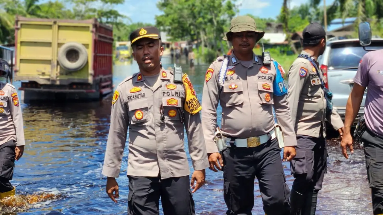 Kapolsek Kubu Babussalam Rokan Hilir mengecek debit air di jalan raya untuk memastikan tidak ada kemacetan.