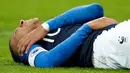 Penyerang timnas Prancis dan PSG, Kylian Mbappe meringis kesakitan setelah terlibat duel dengan kiper timnas Uruguay, Martin Campana dalam laga uji coba di Stade de France, Rabu (21/11). Mbappe mengalami cedera bahu pada menit ke-30. (AP/Christophe Ena)