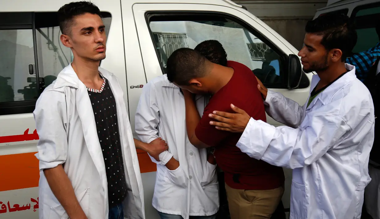 Sejumlah paramedis Palestina menangisi rekan mereka, Abdullah al-Qutati yang meninggal ditembak tentara Israel, Rafah, Jalur Gaza, Sabtu (11/8). (SAID KHATIB/AFP)