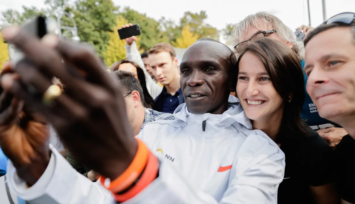 Pelari Kenya, Eliud Kipchoge berswafoto dengan penonton saat memenangkan Berlin Marathon ke-45 di Berlin, Jerman, Minggu (16/9). Kipchoge berlari solo di mayoritas lomba, menandakan superioritasnya di atas para pelari lain. (AP Photo/Markus Schreiber)