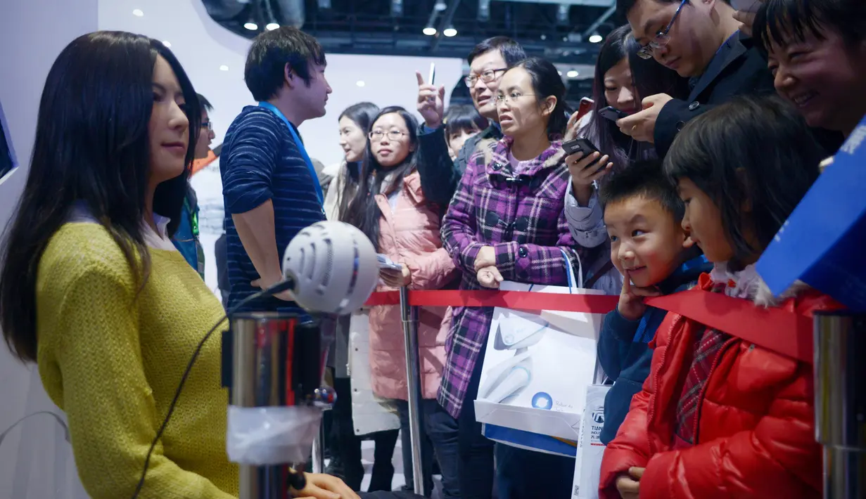 Pengunjung melihat robot humanoid (kiri) selama Konferensi Robot Dunia di Beijing pada 24 November 2015. Wajah dari robot ini sangat mirip dengan manusia bahkan bila disempurnakan makan kita akan susah membedakannya. (AFP PHOTO/WANG Zhao)