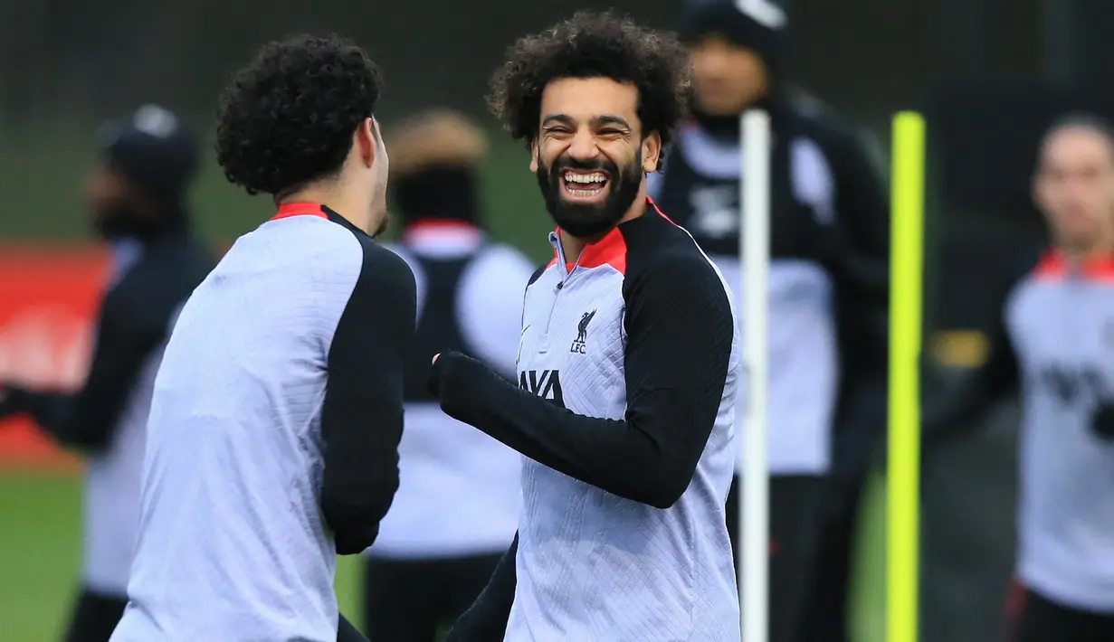 Striker Liverpool, Mohamed Salah bercanda dengan rekannya saat sesi latihan di AXA Training Centre, Liverpool (20/2/2023) menjelang menghadapi Real Madrid dalam laga leg pertama babak 16 besar Liga Champions 2022/2023. Mohamed Salah berpeluang membuat rekor sebagai top skor Liverpool di pentas Eropa jika mampu mencetak minimal satu gol ke gawang Real Madrid dalam laga dua leg. Saat ini Mohamed Salah duduk sejajar dengan legenda Liverpool, Steven Gerrard yang sama-sama mengemas total 41 gol di kancah Eropa. (AFP/Lindsey Parnaby)