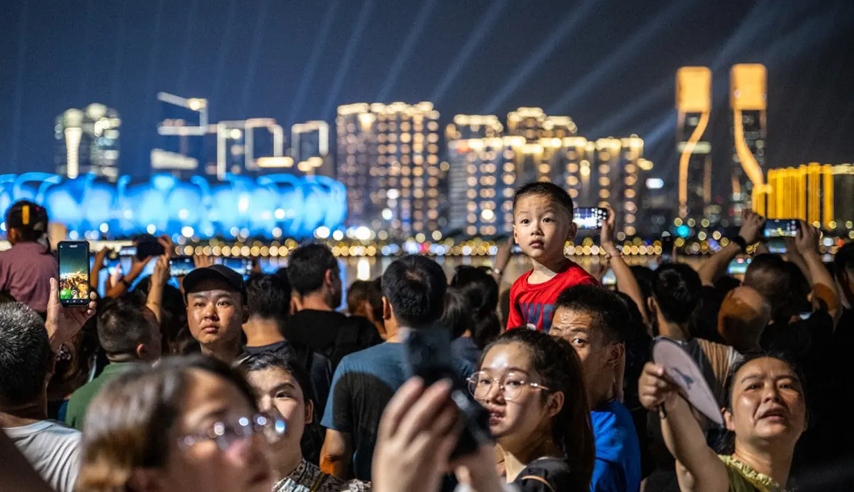 Banyak warga yang datang berbondong-bondong dengan keluarga mereka saat menyaksikan pertunjukan cahaya yang menawan di Hangzhou Olympic Sports Centre Stadium jelang pembukaan Asian Games 2023. (Philip FONG/AFP)